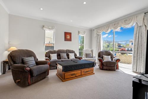 a living room with a couch and chairs and a table at The Oasis in Auckland