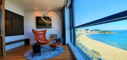 Cette chambre dispose d'une chaise et offre une vue sur la plage. dans l'établissement Kumuda Les Maison, à Busan