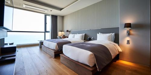 Cette chambre comprend deux lits et une grande fenêtre. dans l'établissement Kumuda Les Maison, à Busan
