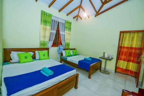 a bedroom with two beds with green and blue pillows at Ella Eco Adventure Point in Bandarawela