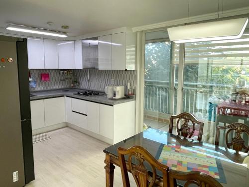 a kitchen with white cabinets and a table with chairs at Haeng Un - For Foreigner & Female Only in Suwon