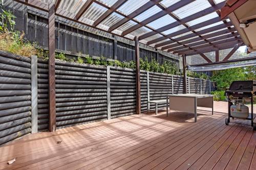 a wooden deck with a pergola and a grill at The Oasis in Auckland