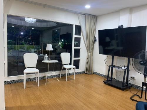 a living room with white chairs and a flat screen tv at Baan Sood Soi Residence 1 บ้านสุดซอย เรซิเด้นท์ 1 in Ban Bang Bamru
