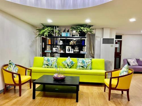 een woonkamer met een gele bank en stoelen bij Baan Sood Soi Residence 1 บ้านสุดซอย เรซิเด้นท์ 1 in Ban Bang Bamru