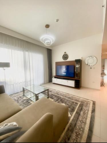 uma sala de estar com um sofá e uma televisão em Luxury cozy private room em Dubai
