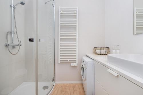 a white bathroom with a shower and a sink at Stylish studio in modern design - Tartaczna 2 by Rent like home in Gdańsk