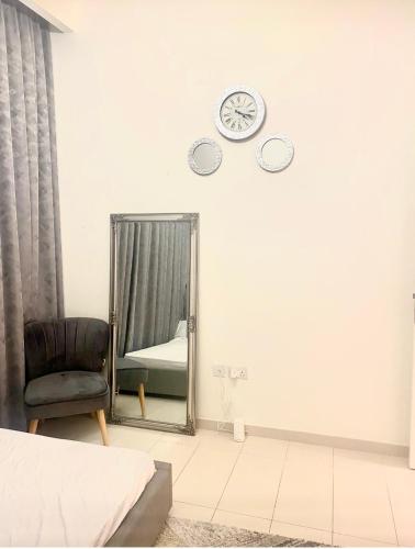 um quarto com um espelho, uma cadeira e um relógio em Luxury cozy private room em Dubai
