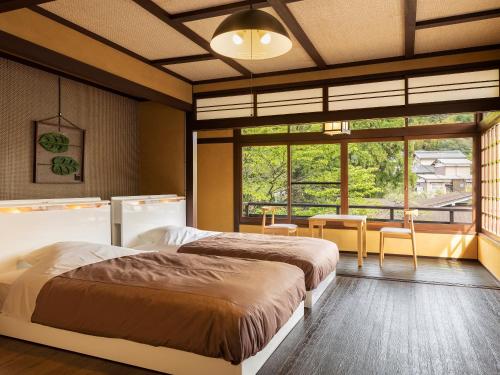 1 dormitorio con 2 camas y ventana grande en Yukai Resort Premium Saiki Bekkan en Misasa