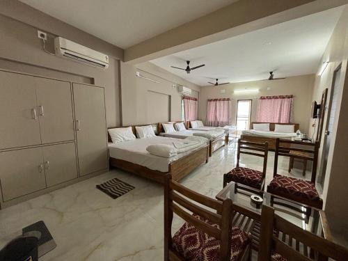 ICHHAMATI HOTEL AND RESTAURANT في Hāsnābād: غرفة معيشة بها سريرين وأريكة