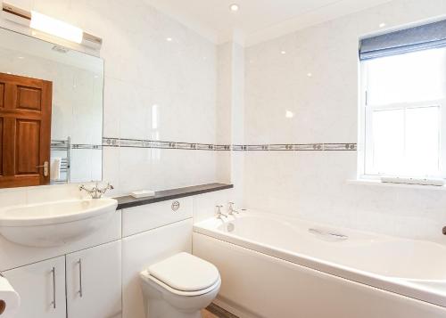 a white bathroom with a toilet and a sink at Green Acres Cottages in Par