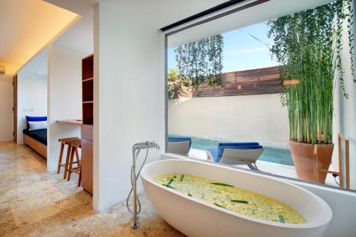 a bath tub in a room with a large window at Uma Sapna in Seminyak