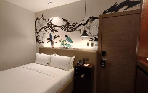 a bedroom with a bed and a wall with flowers at The Henry Hotel Roost Bacolod in Bacolod