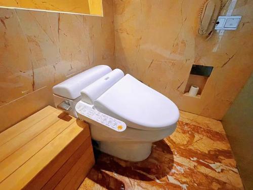 a white toilet in a bathroom with a wooden floor at Rainbow Valley Hot Spring Hotel in Gaizhou