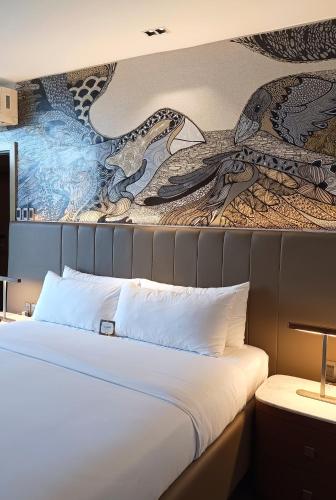 a bedroom with a bed with a painting on the wall at The Henry Hotel Roost Bacolod in Bacolod