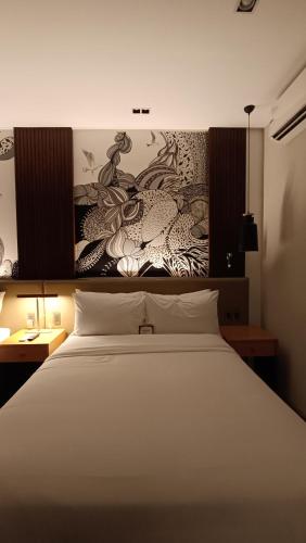 a bedroom with a white bed and a painting on the wall at The Henry Hotel Roost Bacolod in Bacolod