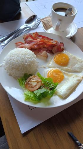 a plate of breakfast food with eggs bacon and rice at The Henry Hotel Roost Bacolod in Bacolod