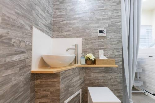 een badkamer met een wastafel en een stenen muur bij 室内をフルリノベーション！清潔なお部屋　ベッド7台　2つのシャワールーム in Osaka