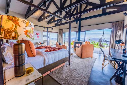 Zulu Rock Lodge - Babanango Game Reserve في Ulundi: غرفة نوم مع سرير وطاولة مع مكتب