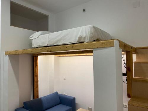 łóżko na górze pokoju z niebieskim krzesłem w obiekcie Estudio 86 B w mieście Torrox Costa