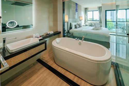 uma casa de banho com banheira e uma cama em The TJ Hotel Jomtien em Praia de Jomtien