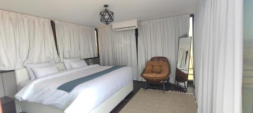 a bedroom with a large bed and a chair at Oman desert private camp in Shāhiq