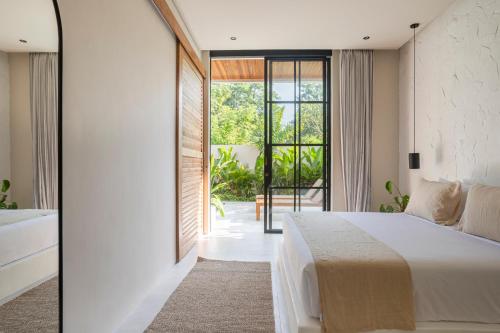 a bedroom with a large bed and a large window at The Dreamland by The Young Villas in Uluwatu