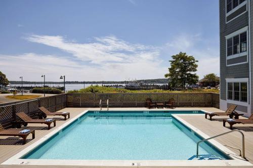 einen Pool mit Stühlen und ein Gebäude in der Unterkunft The Harbor Front Inn in Greenport