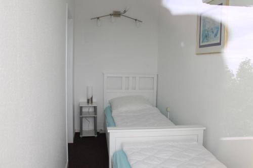 um pequeno quarto com uma cama branca e uma mesa de cabeceira em Ferienwohnung E510 für 2-4 Personen an der Ostsee em Brasilien