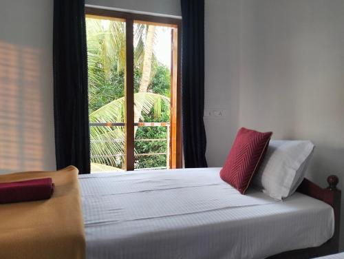 a bedroom with a white bed with a window at KOVIL home's Guest land in Cochin