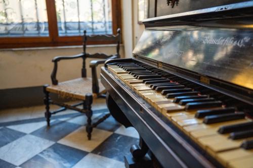 an old piano in a room with a chair at Royal Victoria Hotel in Pisa