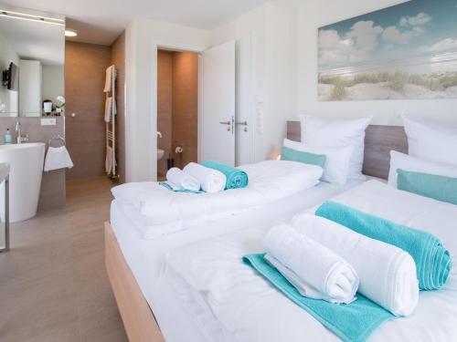 two white beds in a room with a bathroom at Ferienhaus Emily in Hoddersdeich