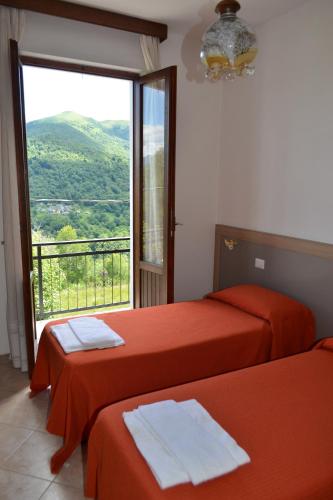 two beds in a room with a large window at Albergo Diana in Tronzano Lago Maggiore
