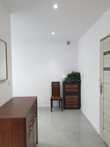 a white room with a dresser and a chair at Noclegi - Pokoje - STEMPO in Skarżysko-Kamienna