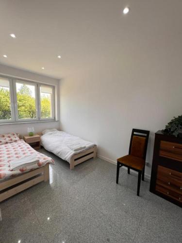 a bedroom with two beds and a chair and a dresser at Noclegi - Pokoje - STEMPO in Skarżysko-Kamienna