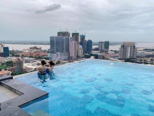 dos personas en una piscina en la parte superior de un edificio en The Penthouse en Phnom Penh