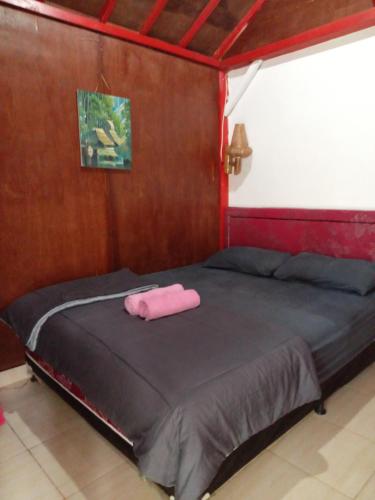 a bed with a pink towel on it in a room at Tereng Wilis Jungle Inn in Tetebatu