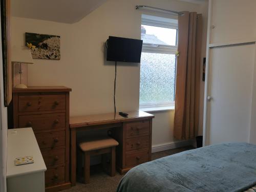 a bedroom with a desk and a dresser and a window at A Bird House in Belper