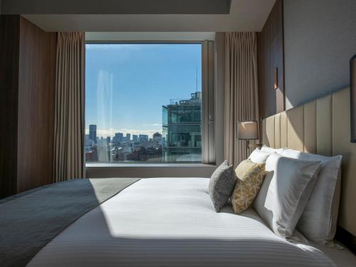 a bedroom with a large bed with a large window at Mitsui Garden Hotel Roppongi Tokyo Premier in Tokyo