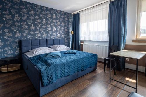 Un dormitorio con una cama azul con papel pintado azul y blanco en Apartamenty Komfort, en Częstochowa