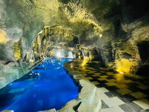 einen Pool in einer Höhle mit blauem Wasser in der Unterkunft Sun Villa Thanh Liên Wyndham Vườn Vua Resort & Villas in Ðồng Phú