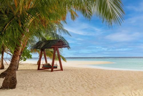 a hammock on a beach with a palm tree at NH Collection Maldives Havodda Resort - Stays of 6 nights or more, 50 percent off domestic flights for 2 person in Gaafu Dhaalu Atoll