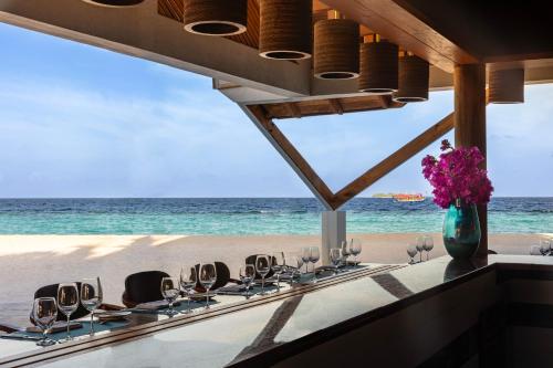 a table on the beach with wine glasses and flowers at NH Collection Maldives Havodda Resort - Stays of 6 nights or more, 50 percent off domestic flights for 2 person in Gaafu Dhaalu Atoll
