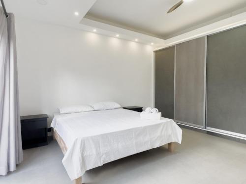 biała sypialnia z białym łóżkiem i oknem w obiekcie Résidence Mo'Villa - Spacious 4 Bedrooms Villa with infinity pool w mieście Grand Baie