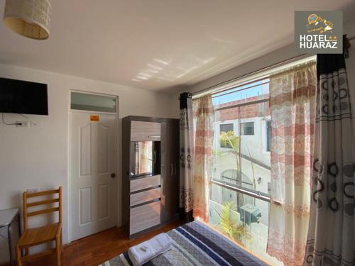 a bedroom with a bed and a large window at HOTEL HUARAZ in Tacna