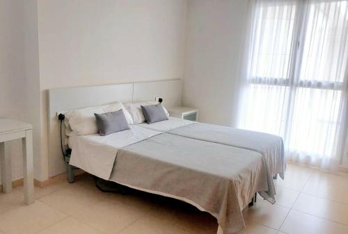 biała sypialnia z dużym łóżkiem z 2 poduszkami w obiekcie BEACH VALENCIA 29 - Luxury Beachfront Apartament w Walencji