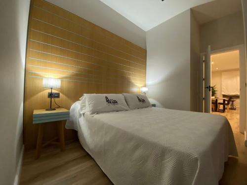 a bedroom with a large white bed with a wooden wall at La Posada de San Miguel in Andújar