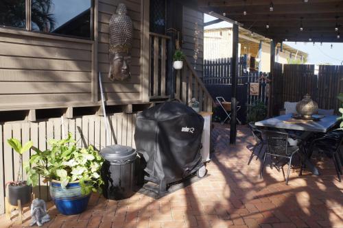 a patio with a table and some plants and a fence at Luxury 4 Bedroom Home with Pool & Games Room Bar in Bargara