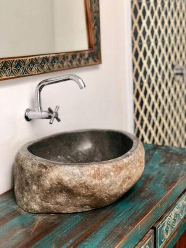 a stone sink in a bathroom with a mirror at The Blue Joglo Jogja in Yogyakarta