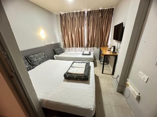 Habitación pequeña con 2 camas y TV. en Haising Hotel en Singapur