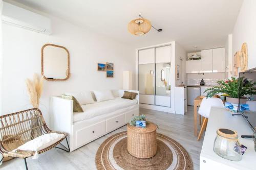 een woonkamer met een witte bank en een tafel bij Les flots turquoise * Climatisation * Plage * Mer in Carnon-Plage